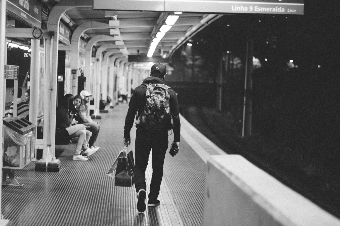 Man walking away down the subway platform with multiple shopping bags. Mia's best sellers, nature in a bottle. Photo courtesy of StockSnap.