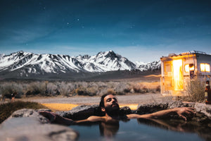 Man enjoying hot springs in the wilderness. Personal care aromatherapy products for men is nature in a bottle. Photo courtesy of UnSplash.