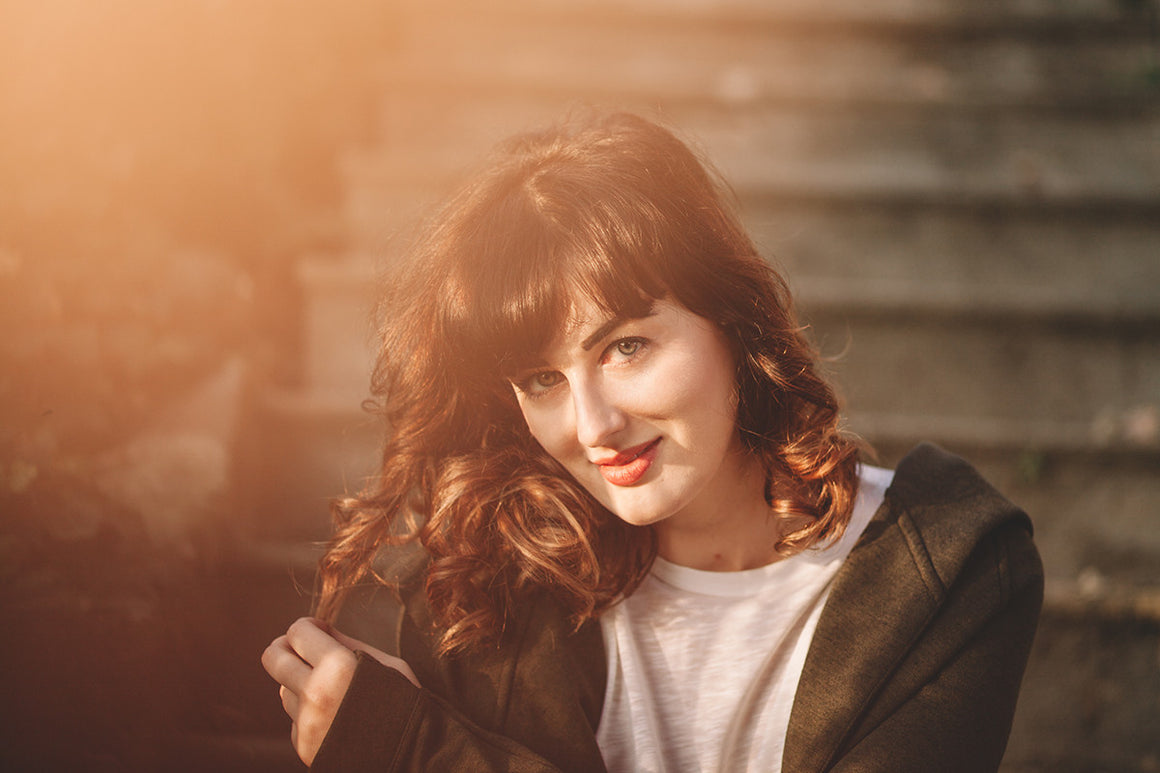 Woman sitting on steps playing with her hair. Aromatherapy for lips and face by Mia's - nature in a bottle. Photo courtesy of SplitShire.